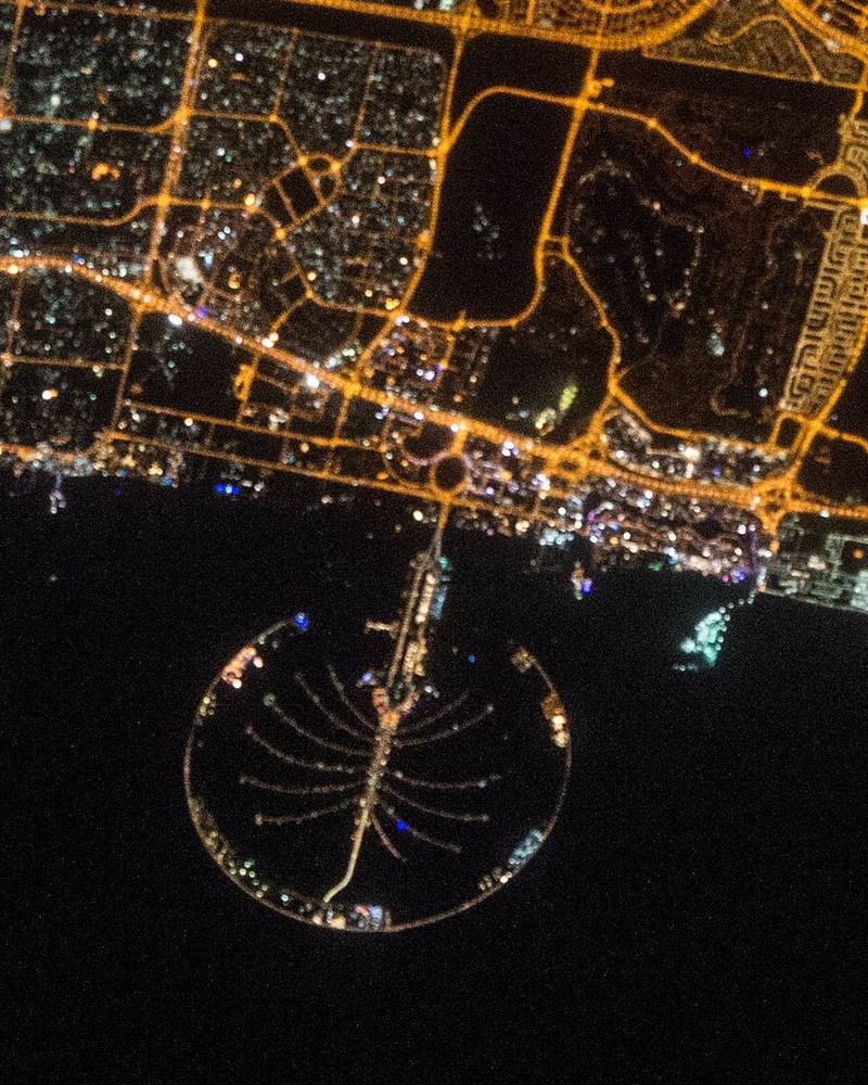Dubai at night from space, with Palm Jumeirah lit in the sea below the coast road