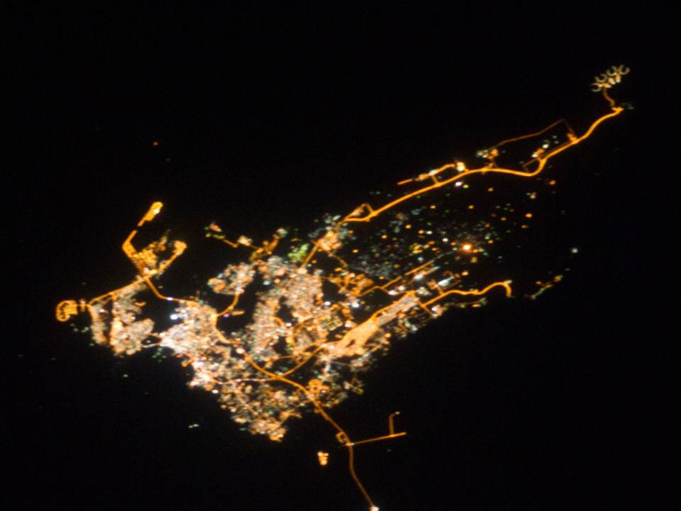 Bahrain at night from space, the island's towns joined by lit roads in a dark sea