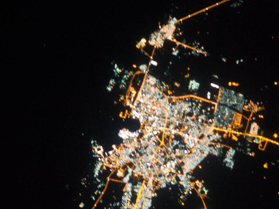 Doha at night from space, the city's lights spreading from the bay along its roads
