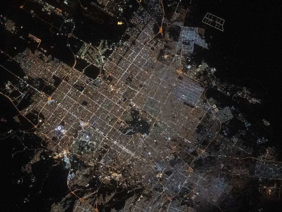 Riyadh at night from space, a wide grid of white and amber light in the desert